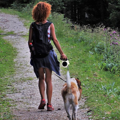 femme promene chien foret avec laisse chien enrouleur blanc